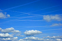 Vapour trails from aircrafts among clouds in a blue sky, France