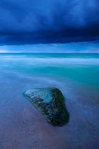 Rock in Baltic Sea surrounded by water at dusk with stormy clouds, Kreptitz, Mecklenburg-Vorpommern, Germany, August