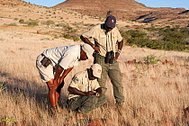 Save the Rhino Trust trackers, Erwin Karatjiva (crouching) and Dansiekie Ganaseb(right), with Wilderness Safaris guide Gotlod Hawaxab (left), recording black rhino sighting, Palmwag concession, Kunene...