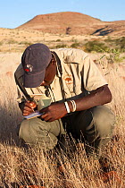 Save the Rhino Trust tracker Dansiekie Ganaseb, recording black rhino sighting, Palmwag concession, Kunene region, Namibia, May 2009. Editorial use only