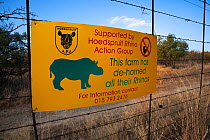 Sign on game farm perimeter fence to deter rhino poachers explaning rhinos there have been dehorned, Hoedspruit, Limpopo, South Africa, June 2012. Editorial use only.