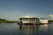 Floating house doubling as a small store for the locals selling produce, oil and gasoline on the Rio Negro. Amazonia, Brazil, June 2012