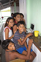 Children using a laptop on a floating house on the Rio Negro, Amazonia, Brazil, June 2012