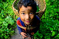 A young boy carrying basked in Budhi Gandaki river valley. Manaslu Conservation Area, Himalayas, Nepal, October 2009.