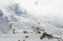Buddhist prayer flags at high altitude in the Larkya La (5.106m) in snow, Manaslu Conservation Area, Himalayas, Nepal, October 2009.
