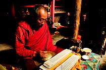 Bhojo Buddhist monastery with monk reading sacred text (3.500m), Manang. Annapurna Conservation Area, Himalayas, Nepal, October 2009.