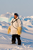 Man wearing traditional polar bearskin gloves stands on pack ice over the Chukchi Sea. Offshore from Barrow, Arctic coast of Alaska, spring, May 2012.