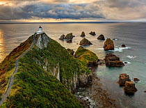 RF- Nugget Point (Ka Tokata) lighthouse at sunrise, rain clouds sweeping in from the horizon. Catlins, Clutha District, Otago, South Island, New Zealand. October, 2006. (This image may be licensed eit...