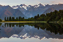 Late evening light on the Souttern Alps being perfectly relected in the calm waters of Lake Matheson. New Zealand's highest mountain, Mount Cook or Aoraki (3754m) is on the right, and Mount Tasman (34...