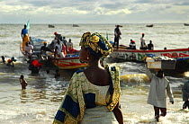 Woman looking out to sea as fishermen arrive on the beach in Mbour, in the 'Petite Cote', south of Dakar, Senegal, September 2006.