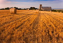 Salthouse Church, stubble field and straw bales after harvest Norfolk, UK, August