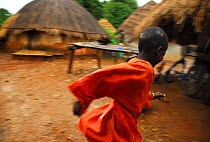 A boy runs in the rain in a Bassari village. Bassari country, east Senegal. This area became a UNESCO World Heritage site in 2012, for cultural landscape and traditions kept by the the Bassari, Fula a...
