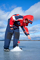 Ice fishing on a freshwater lake, Sweden, April 2008