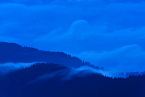 Leota Mountain range silhouetted at twilight with clouds, Arges county, Carpathian Mountains, Romania, July