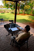 Nature photographer Oriol Alamany editing photographs on his laptop at Lower Sabie Camp, Kruger National Park, Transvaal, South Africa, September.