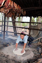 Lena Kuboleva, a young Selkup woman, making traditional Selkup bread by baking dough in hot sand at her family's summer camp in the forest, Krasnoselkup, Yamal, Western Siberia, Russia.