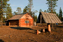 Log cabin at a Selkup summer camp in the forest with a traditional raised wooden food storage hut (to avoid rodent problem) Krasnoselkup, Yamal, Western Siberia, Russia