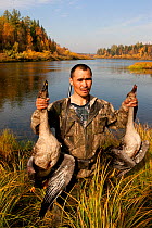 Vassily Korgachev, a Selkup hunter, holds up two geese he has shot for food on the River Shirta in the autumn, Krasnoselkup, Yamal, Western Siberia, Russia