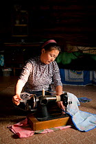 Lena Kuboleva, a young Selkup woman, using a sewing machine on the floor of her family's log cabin, Krasnoselkup, Yamal, Western Siberia, Russia
