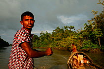 Men on a wooden boat who use smooth-coated otters (Lutra perspicillata) for traditional fishing practices,  the Sundarbans National Park, the largest mangrove swamp in the world. Bangladesh. UNESCO Wo...