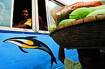 Man carrying melons watched by people on a bus, Dhaka, Bangladesh June 2012.