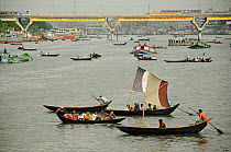 Boats on the Sadarghat water front, Dhaleshwari river, with a bridge in the background. Dhaka, Bangladesh, June 2012.