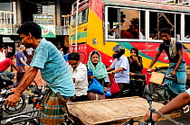 A busy street with people walking,  and cycling through Dhaka, Bangladesh, June 2012.