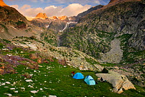 Hikers with tents at dawn in the valley of Remuae, Posets-Maladeta Natural Park, Ribagorza, Pyrenees, Huesca, Aragon, Spain. Model released.