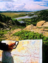 Hiker orienting a map with a compass in Estanys de Les Bouillouses, Pyrenees Catalanes Natural Park,  Languedoc-Roussillon, France