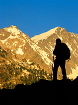 Woman hiker silhouetted at sunrise in Conangles valley, Aran Valley, Pyrenees, Catalonia, Spain. Model released