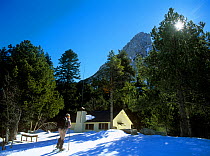 Hiker with snowshoes arriving at Ernest Mallafre mountain hut, Aiguestortes i estany de Sant Maurici National Park, Catalonia, Pyrenees, Spain, Model released.