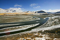 Landscape of Tibetan Plateau, with stream flowing through and mountains in the distance. Kekexili, Qinghai, Tibetan Plateau, China, December 2006