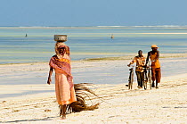 Local people walking along Jambiani Coast,  Zanzibar Island, Tanzania, October 2008