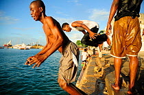 Local men jumping into the water from  jetty in Port Stone, Zanzibar Town, Zanzibar, Tanzania