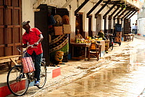 Man on bicycle near shop stands in Stone Town, Zanzibar, Tanzania, October 2008