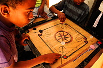 Children play a board game in the old city, Stone Town, Zanzibar, Tanzania