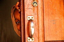 Girl peeping out from behind door,  Stone Town, Zanzibar, Tanzania. No release available.
