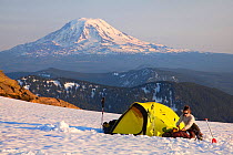 Woman at campsite at high altitude in the Goat Rocks Wilderness with a view of Mount Adams in the distance, Washington, USA. July 2012. Model released