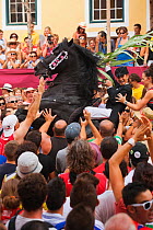 Lady riding a black Menorquin stallion, performing the bot or walking courbette of the Doma Menorquina, during the festival Mare de Deu de Gracia, in Mahon, Menorca, Spain 2012.  Tourists are trying t...