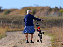 Woman pushing her bike. Breton marshes, west France, September 2012.