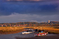 View towards Blakeney village with boats and stormy clouds, Morston Quay, Norfolk, November 2012