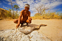 A Zu/'hoasi Bushman in the Kalahari makes an arrow. Heating the stick in the embers of the fire softens the fibres and allows the stick to be straightened. Kalahari, Botswana. April 2012.