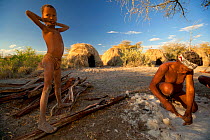 A Zu/'hoasi Bushman scrapes hair from an animal hide while a child watches. Kalahari, Botswana. April 2012.