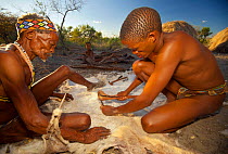 Zu/'hoasi Bushmen prepare the hide of a goat by removing the hair. With restrictions on the animals that they are allowed to hunt, Bushmen communities rely on these animals for food, clothing, quivers...