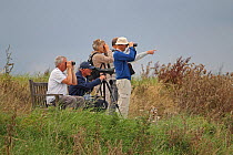 Birdwatchers looking through binoculars and scope RSPB Titchwell, Norfolk, UK, September 2012.