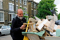 Man looking at clothes hanger he has found in a skip, Highbury, London Borough of Islington, UK