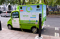 Seymour Green mobile electric powered recycling vehicle for bottles and cans in Central London street, recharging at juice point, UK