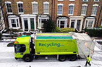 Recycling truck in snow with council worker in street, Holloway, London Borough of Islington, UK