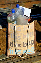 Reusable cotton bag with plastic bottles for use as garden cloches within, London UK