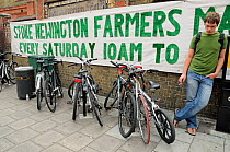 Sign outside Stoke Newington Farmers Market with parked bicycles and man, London Borough of Hackney, UK, August 2009